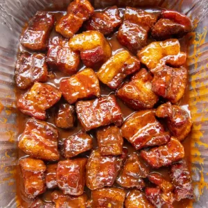 Fully cooked pork belly burnt ends in sauce.