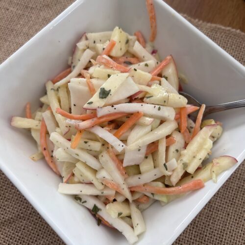 homemade kohlrabi slaw in a white bowl.